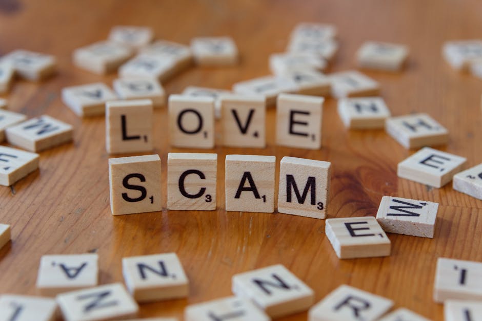 A flat lay image showing various gambling chips and cardboard currency notes arranged on a light grey surface. The chips are in shades of white, grey, and black with denominations of £10, £25, and £50 visible. The paper notes include a green £100 note and a smaller green £50 note, both positioned near the chips. In the center of the image, four small wooden blocks spell out the word 'SCAM' with black letters on natural wood backgrounds, indicating a warning about fraudulent activity. The items are arranged in a way that suggests discussion or awareness of financial scams, with no interaction or movement visible. The scene is well-lit and offers a clear, neutral perspective suitable for content related to house removals or moving services, subtly emphasizing the importance of verifying legitimacy during transactions or bookings related to relocation services, such as those provided by Man and Van Harringay.